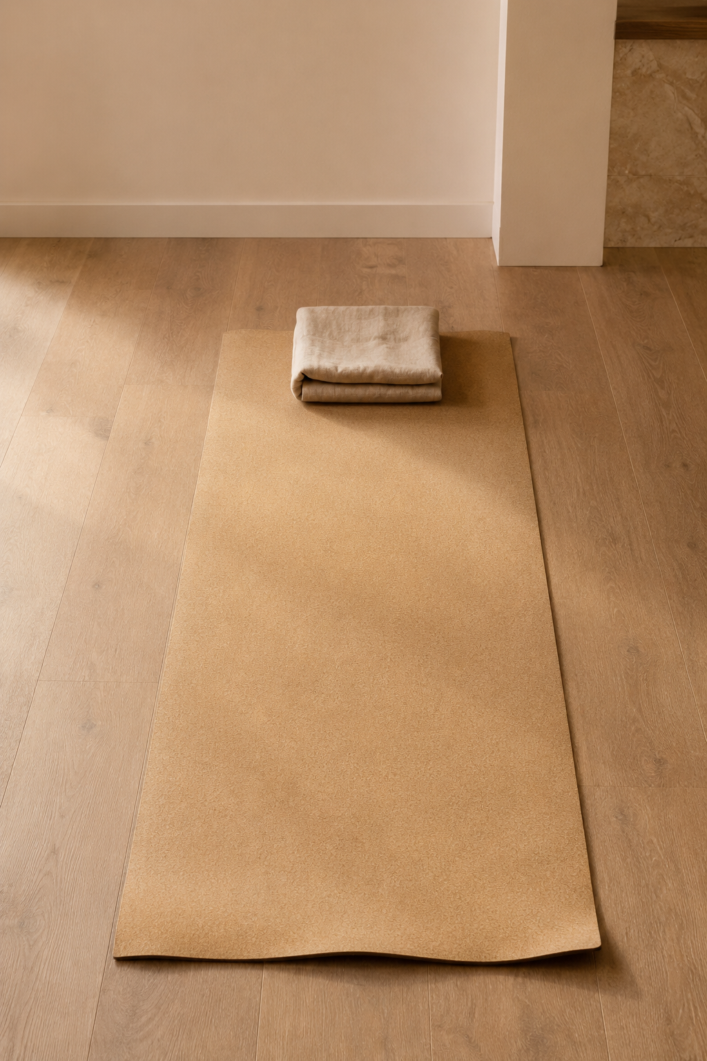 Tapis de Pilates en liège naturel déroulé sur le sol chêne avec serviette en lin pliée, séance Pilates Mat